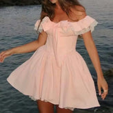 Woman wearing a pink off-shoulder dress by a body of water